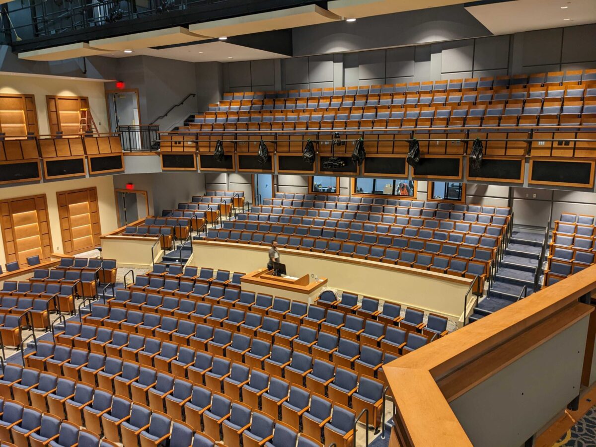 interior of a large school auditorium with a balcony, acoustic panels, and a mix position visible