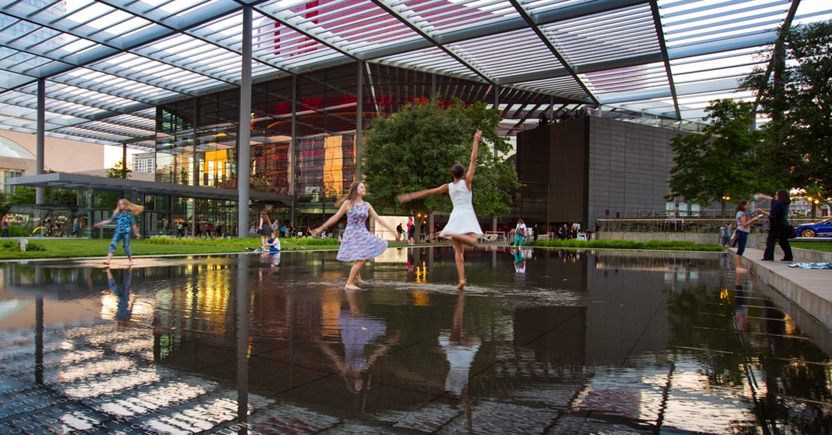 two children dancing in a puddle under an awning outside of a theatre